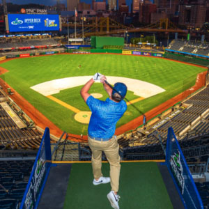 Man swinging golf club from baseball field bleachers